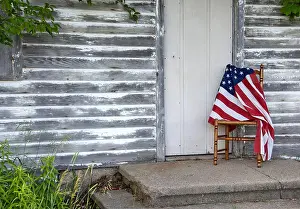 4th Of July Prints: American flag draped over old wooden chair by rustic house door