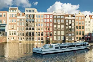 Amsterdam canal cruise ship with Netherlands traditional house in Amsterdam, Netherlands