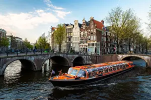 Amsterdam canal cruise ship with Netherlands traditional house in Amsterdam, Netherlands