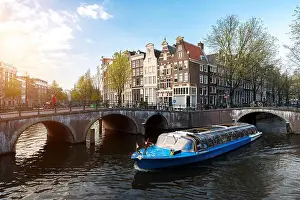 Amsterdam canal cruise ship with Netherlands traditional house in Amsterdam, Netherlands