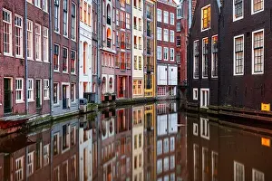 Amsterdam, Netherlands with narrow canals and buildings lining them in the morning time