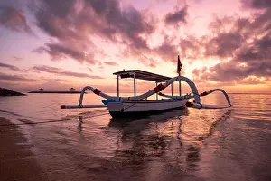 Blue Boat Prints: Ancient traditional Janggolan fishing boat on seashore at colorful sunrise