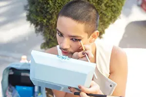 Eyeliner Prints: Androgynous male applying eyeliner while doing makeup and looking in mirror