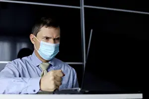 Headache Prints: Angry man in face mask and office clothes banging his fist on the table while sitting at laptop