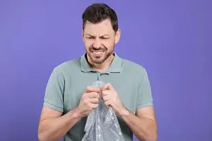 Anxious Prints: Angry man popping bubble wrap on purple background. Stress relief
