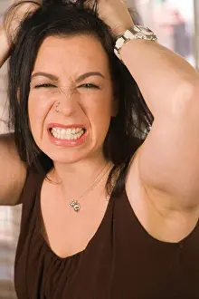 Angry young woman grits her teeth and pulls her hair out in frustration, USA