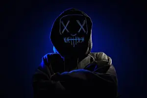 Hood Prints: Anonymous man in a hoodie hiding face behind neon glow scary mask on dark background
