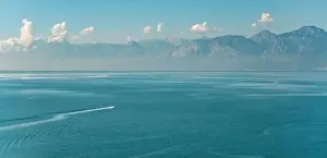 Island Bay Prints: Antalya landscape with a boat sailing on the sea and mountains in the background