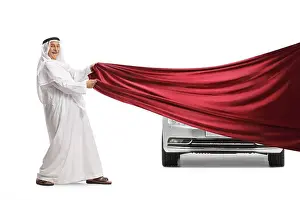 White Work Prints: Arab man in traditional clothes pulling a red piece of cloth in front of a car isolated on white background