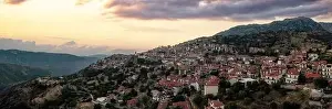 Arachova Greece mountain town aerial panoramic view. Traditional houses and stone tower clock cloudy sky at sunset