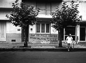 Dictator Prints: ARG 257A Mar Del Plata Argentina political grafitti POR UN POLO OBRERO Y SOCIALISTA street scene with man crossing road