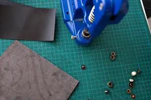 Cast Iron Prints: Artisan using hand press for setting snaps in leather for makes a wallet