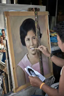 Easel Prints: Artist painting a female portrait from a photograph