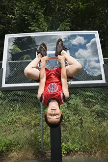 Mischief Prints: Asian boy hanging upside down on basketball hoop