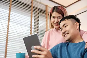 Embracing Prints: Asian couple watching video live on tablet on sofa in living room at home
