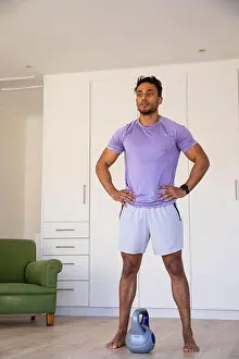 Kettlebell Prints: Asian man standing barefoot on wood floor in home workout space with grey kettlebell
