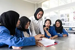 Coaching Prints: Asian Muslim teacher instructing a group of attentive students in a classroom setting