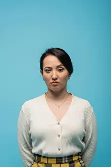 Skirt Prints: Serious asian woman in cardigan looking at camera isolated on blue