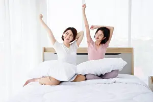 Awake Prints: Two Asian women wake up and stretch on bed in morning