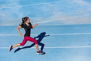 Jogging Prints: Athlete runner running on athletic track training her cardio