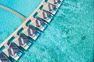 Atolls and islands in Maldives. Tropical island at Maldives with luxury water villas, bungalows over amazing blue sea. Summer vacation, aerial view