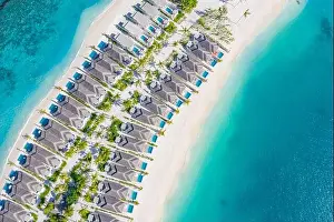 Atolls and islands in Maldives. Tropical island at Maldives with luxury water villas, bungalows over amazing blue sea. Summer vacation, aerial view