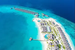 Atolls and islands in Maldives. Tropical island at Maldives with luxury water villas, bungalows over amazing blue sea. Summer vacation, aerial view
