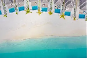 Atolls and islands in Maldives. Tropical island at Maldives with luxury water villas, bungalows over amazing blue sea. Summer vacation, aerial view