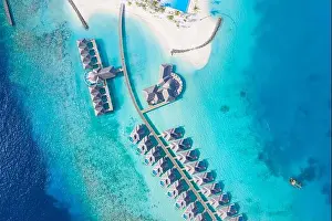 Atolls and islands in Maldives. Tropical island at Maldives with luxury water villas, bungalows over amazing blue sea. Summer vacation, aerial view