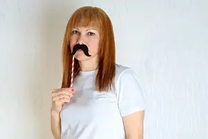 Menopause Prints: Attractive happy middle aged woman having fun with a fake moustache on stick