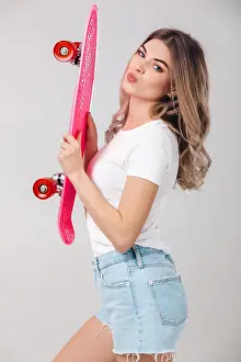 Kiss Prints: attractive woman blonde in white t-shirt and denim shorts holding pink skateboard