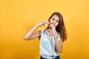 Grimace Prints: Attractive woman in blue denim shirt showing shape of heart gesture