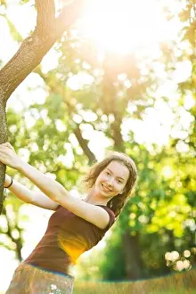 Stretched Prints: Attractive young girl is posing at tree, sunlight goes through trees in background