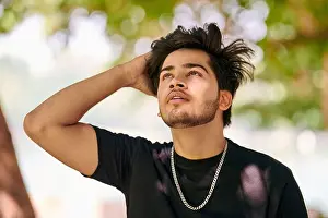 Charming Prints: Attractive young indian man portrait in black t shirt and silver neck chain on outdoor green park background