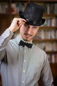 Aristocrat Prints: Attractive young man wearing top hat and bow tie, looking at camera. Indoors shot