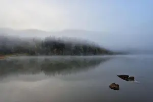 Autumn landscape in the mountains with trees reflecting in the water at St. Ana's lake, Romania
