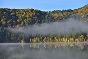 Autumn landscape in the mountains with trees reflecting in the water at St. Ana's lake, Romania