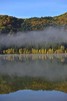 Autumn landscape in the mountains with trees reflecting in the water at St. Ana's lake, Romania