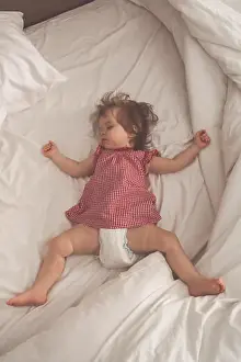 Yawn Prints: Baby girl sleeping on back with open arms and without pacifier in a bed with white sheets