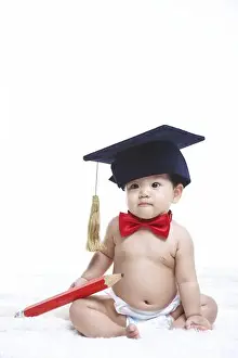 Infant Prints: A baby sits on a white background, wearing a graduation cap and holding a giant pencil.