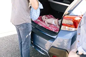 Diaper Prints: Baby smiles up at her father as he dresses her in the trunk of car