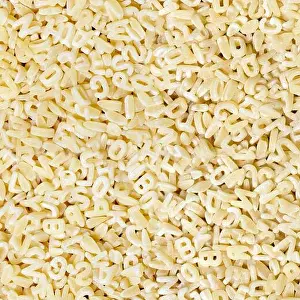 Scattered Prints: Background ore seamless pattern of raw pasta letters close-up