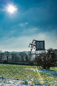 Gloucestershire Prints: Backlit ruined wind driven water pump on a bright winters day with snow on the ground