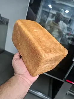 Oven Prints: A baker proudly displays a golden-brown loaf of bread in a modern kitchen