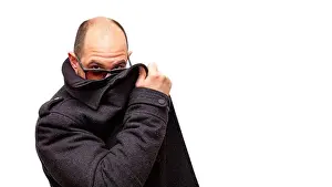 Unrecognizable Prints: A bald adult male wearing sunglasses hides behind his dark jacket and peers over his glasses