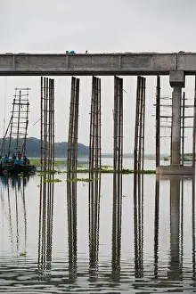 Cows Prints: Bamboo support of a concrete bridge reflected in the water of the river Meghna near Mymensingh
