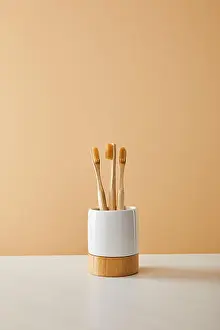 bamboo toothbrushes in holder on white table and beige background