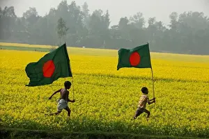 Scenic Beauty Prints: Bangladeshi rural children run with Bangladeshi national flag through a mustard field at Chalan Beel in Natore
