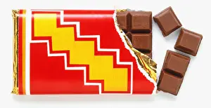 Bar of milk chocolate with one corner unwrapped and four squares broken off, close up