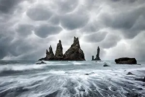 Basalt rock formations Troll toes on black beach with stormy sky with menacing mammatus clouds on background. Reynisdrangar, Vik, Iceland